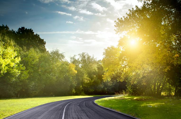Route asphaltée dans la nature avec coucher de soleil