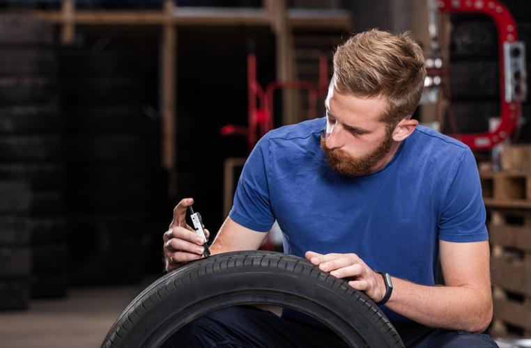 Homme t-shirt bleu avec jauge de profondeur de pneu de voiture mesure pneu