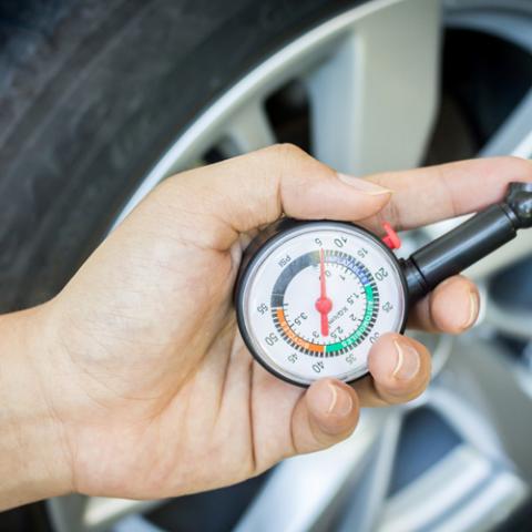 hand met bandenspanningsmeter voor autoband