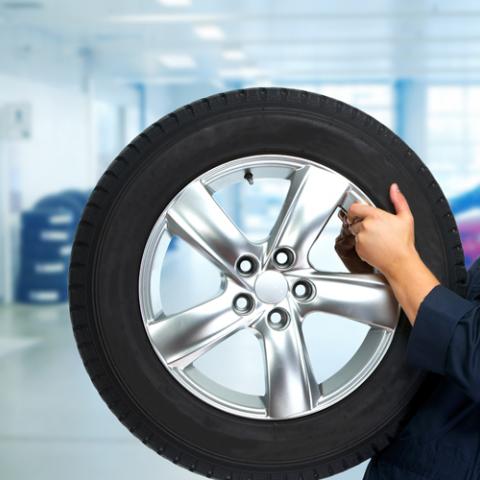 Homme a un pneu en main dans un garage